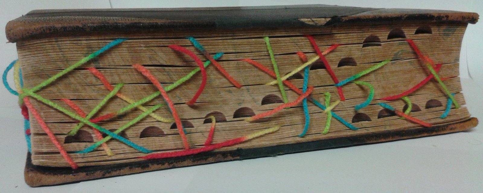 An old book threaded with colourful wool